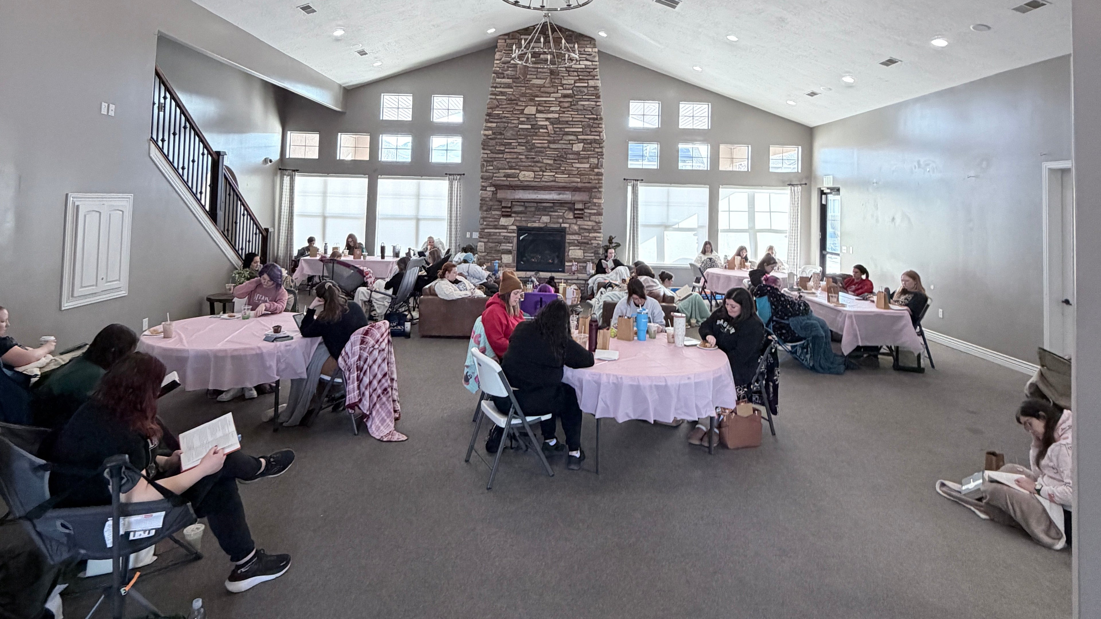People sitting at tables in a modern indoor setting with large windows.