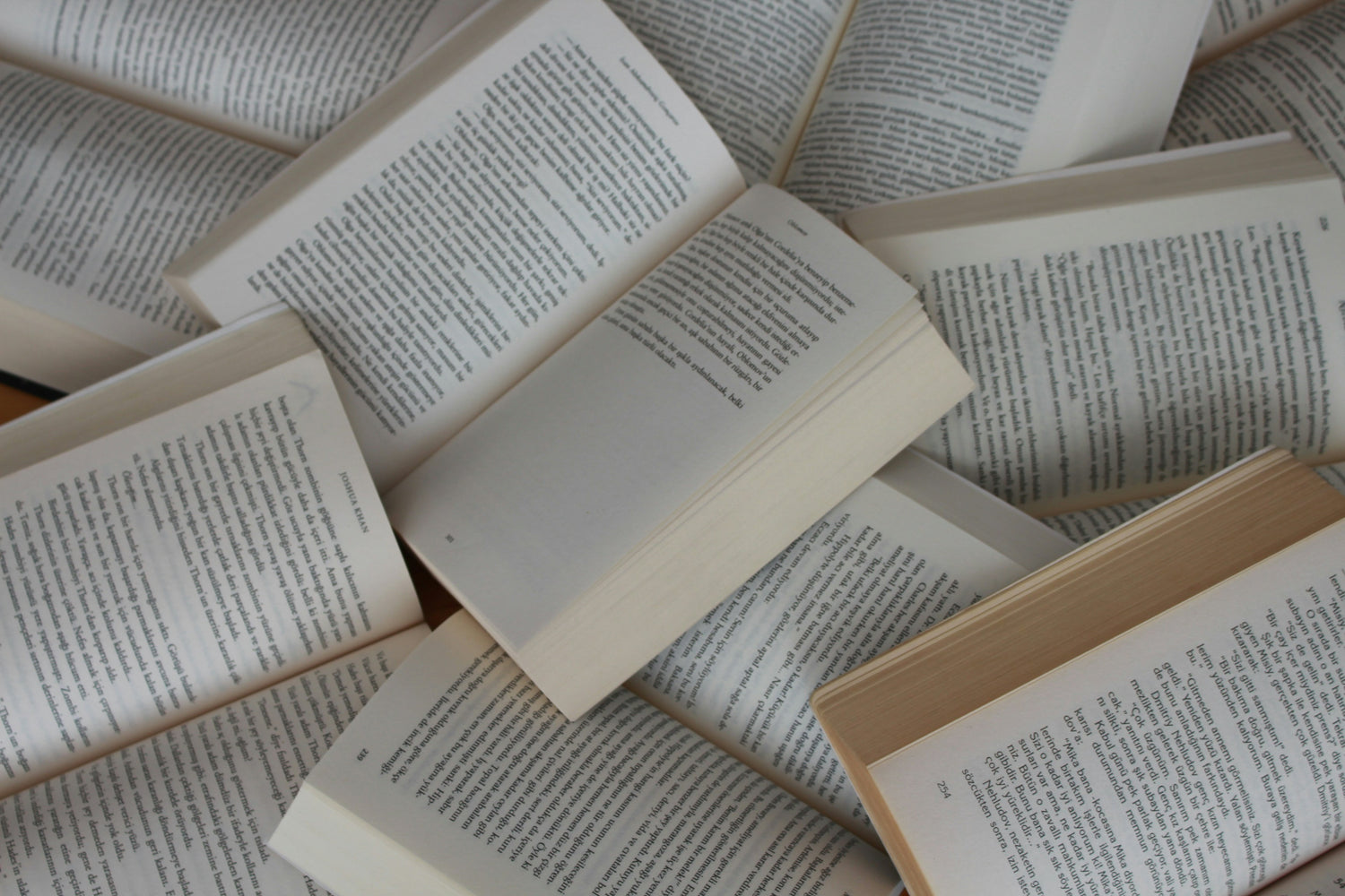 Stack of open books with visible text on a neutral background